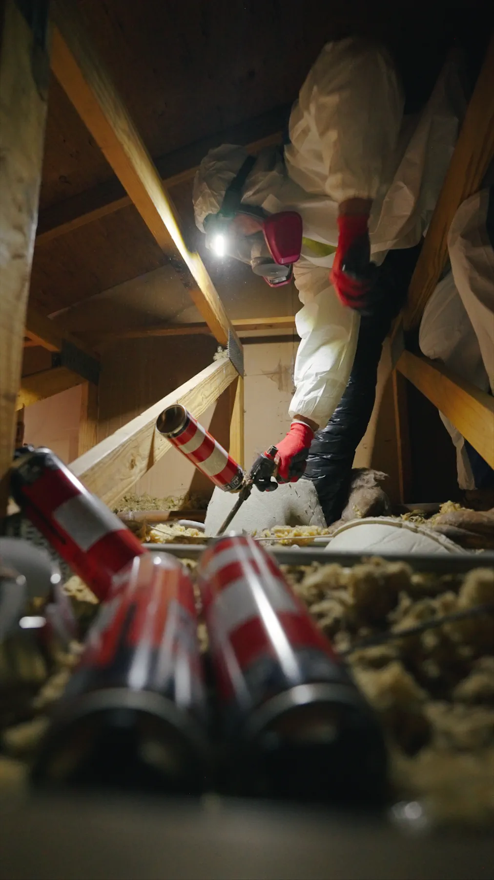 Building Energy Experts worker using a sealant gun inside an attic