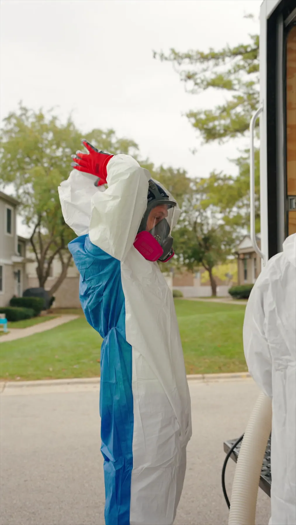 Building Energy Experts worker putting on protective equipment beside a work trailer at a multifamily property